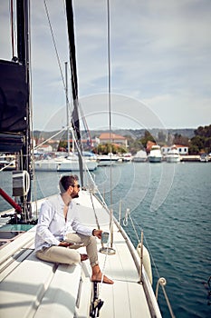A young man is enjoying a view while sitting on a yacht at sea and using a tablet. Summer, sea, vacation