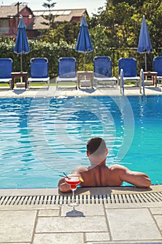 Young Man enjoys in swimming pool with cocktail alcohol drink, Holiday relax and sunbathe