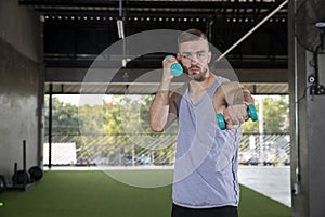 Young man exercise using dumbbells at fitness center.  Determined men  lifting weights  for workout in gym