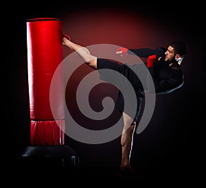 Young man exercising bag boxing in studio