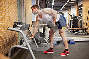 Young Man Exercising With Dumbbell At Gym