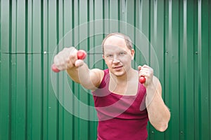 Young man is exercising with dumbbells