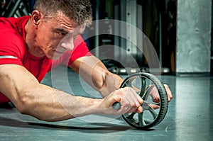 Young man exercising fitness workout for abdominal with toning wheel