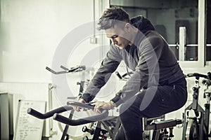 Young man exercising in gym: spinning on stationary bike