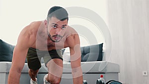 Young man exercising at home. Guy doing mount climber exercise on floor holding hands on mat. Persistant man training