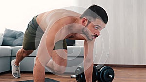 Young man exercising at home. Persistant guy stand in plank position on yoga mat and start doing mountain climber