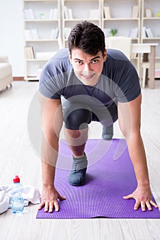 Young man exercising at home in sports and healthy lifestyle con