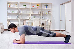 Young man exercising at home in sports and healthy lifestyle con