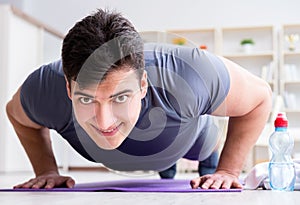 Young man exercising at home in sports and healthy lifestyle con
