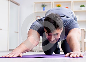 Young man exercising at home in sports and healthy lifestyle con