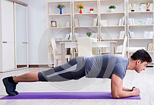 Young man exercising at home in sports and healthy lifestyle con