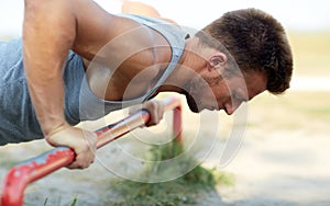 Young man exercising on horizontal bar outdoors