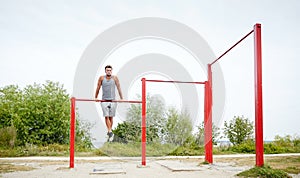 Young man exercising on horizontal bar outdoors