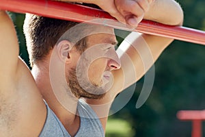 Young man exercising on horizontal bar outdoors