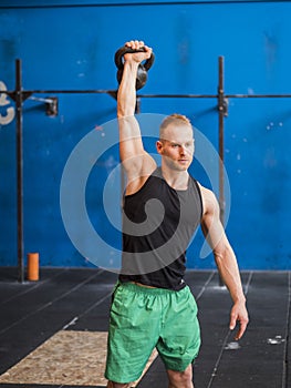 Young man exercising with kettlebells in gym