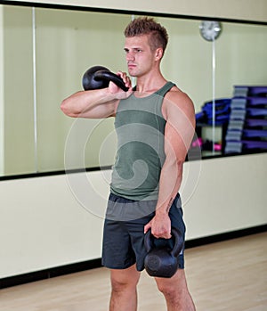 Young man exercising with kettlebells in gym