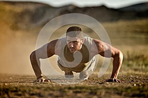 Young man exercising outdoor on dusty field