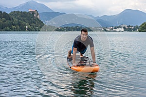 Young man exercising on paddle board at the lake