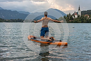 Young man exercising on paddle board at the lake