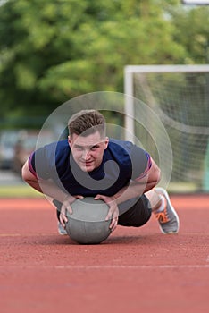 Young Man Exercising Push-Ups On Medicine Ball Outdoor