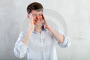 Young man experiencing acute headache in living room