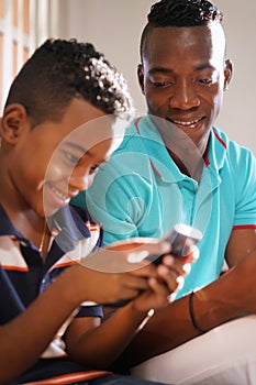 Young Man Explaining Mobile Phone Internet To Son At Home