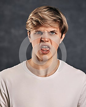 young man expressing negativity on gray background.