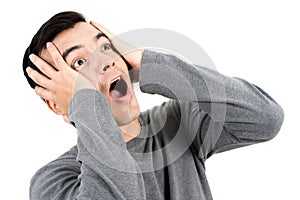 Young man expressing shocked face with hands on head