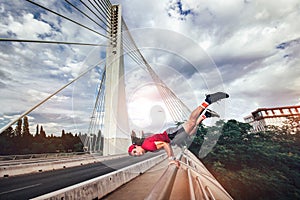 Young man extreme exercising on the bridge.