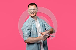 young man in eyeglasses holding revolver and smiling at camera isolated