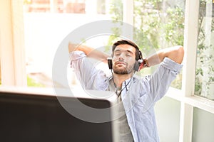 A young man  eyes closed, listening to music using headphones