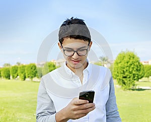 Young man with eyewear in garden looking in smart phone.