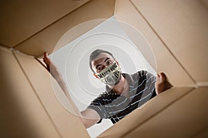 Young man in face mask with sign masks for 100 days in USA opening the biggest postal package