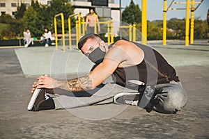 Young man with face mask stretching before calisthenics training