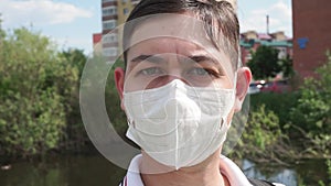 Young man face with medical mask stands at nature. close up,corona virus