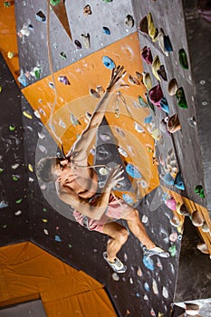 Young man falling down while being belayed in indoor climbing gym