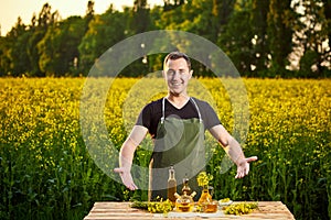 A young man farmer or agronomist examines the quality of rapeseed oil on a rape field. Agribusiness concept