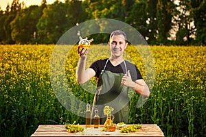 A young man farmer or agronomist examines the quality of rapeseed oil on a rape field. Agribusiness concept