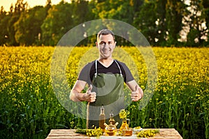 A young man farmer or agronomist examines the quality of rapeseed oil on a rape field. Agribusiness concept