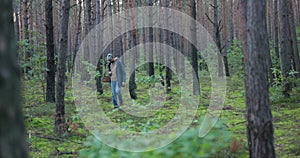 A young man fascinated with mushrooming in free time walks through the forest with a basket in hand in search of