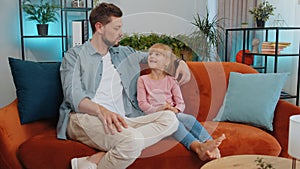 Young man father having trustworthy conversation, talking with daughter child kid at home sofa