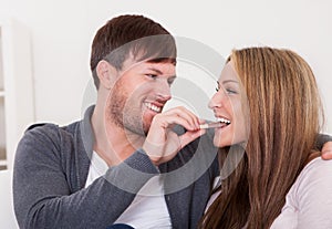 Young man feeding chocolate bar to his girlfriend