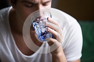 Young man feeling thirsty dehydrated holding glass drinking wate