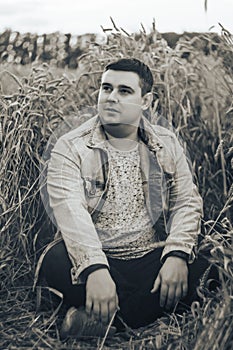 A young man in a field with green wheat