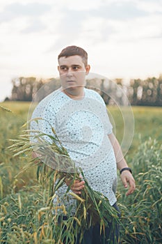 A young man in a field with green wheat