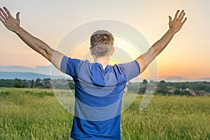 Young man in a field of wheat at sunset