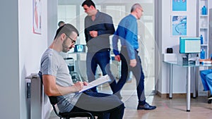 Young man filling documents in hospital waiting area