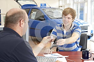 Young man filling in paperwork in car showroom