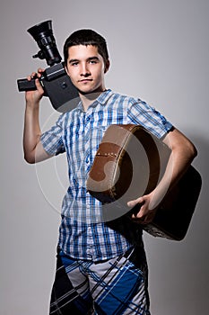 Young man filmmaker with old movie camera and a suitcase in his