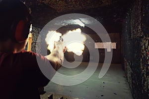 Young man firing a gun at a shooting range the precise moment of